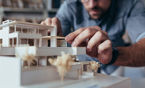 Male architect hands making model house Close up of male architect hands making model house. Man architect working in the office. architectural model photos stock pictures, royalty-free photos & images