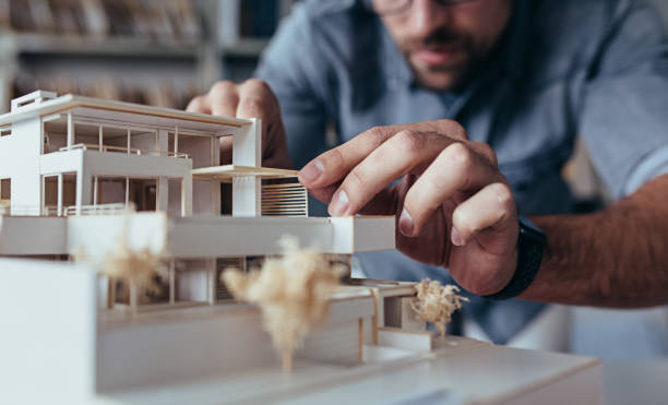 Male architect hands making model house Close up of male architect hands making model house. Man architect working in the office. architectural model stock pictures, royalty-free photos & images