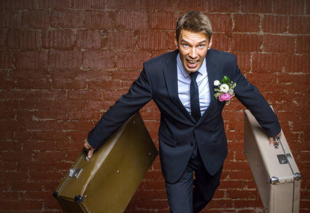 istock groom in a suit and two suitcases runs away 823348326