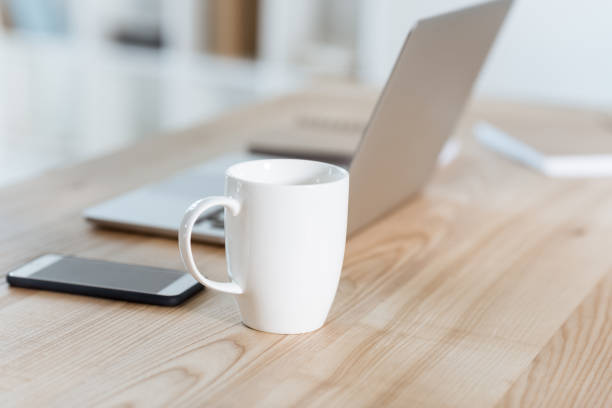 istock selective focus of coffee cup standing on table with digital devices in office 823348340