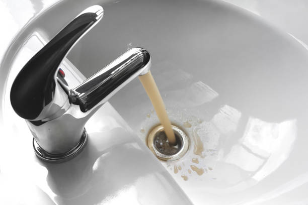 Water Tap With Running Dirty Muddy Water in a Sink stock photo