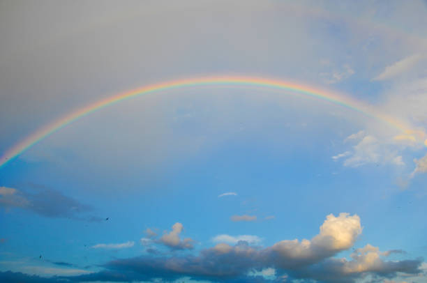 clouds with a rainbow. Multicoloured curved strip in the firmament, as a consequence of the refraction of sunlight in raindrops.