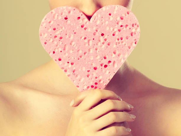 istock woman holding pink heart sponge in hands. 823360162