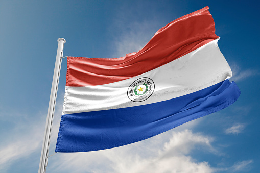 Bandera de Paraguay está agitando contra el cielo azul photo