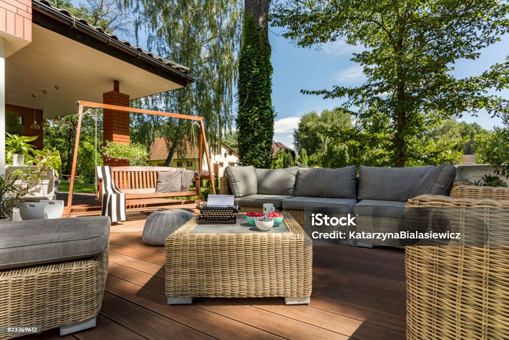 Cozy terrace with wicker furniture Cozy terrace with wicker furniture and wooden garden swing Clear Sky Stock Photo