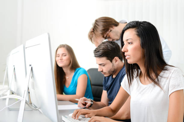 istock group of young people in a business school office classroom working on desktop computer with teacher 823377548