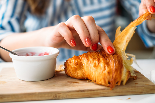 woman eating croissant with jam