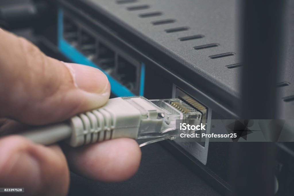 Person plugging in cable to wireless router Person plugging in cable to wireless router. Close up. Network Connection Plug Stock Photo