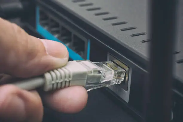 Person plugging in cable to wireless router. Close up.