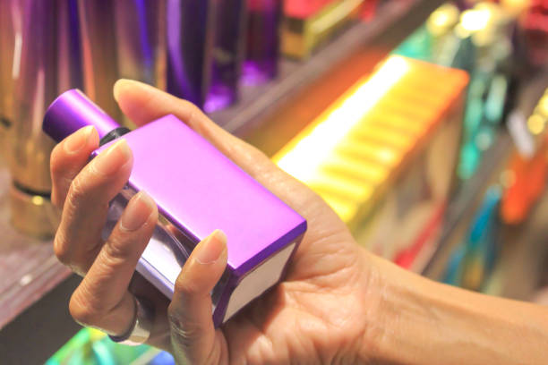 Young women shopping eau de toilette. Close up on female hands holding a purple container of eau de toilette