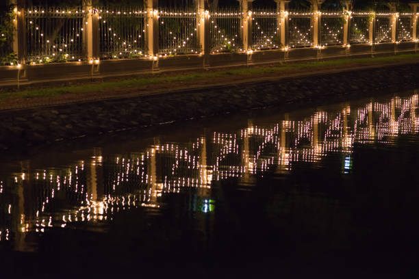 istock Decorated bulbs hanged on wall with reflection of canal at night 823403438