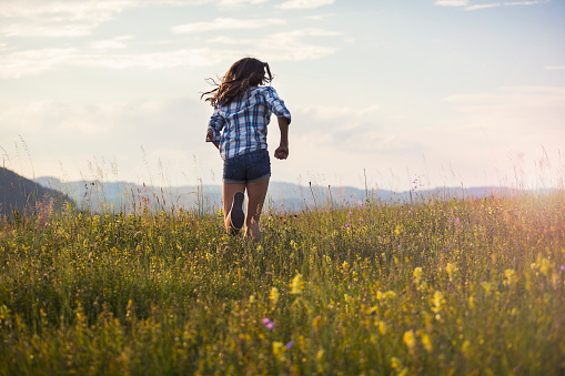 Happy girl running on a mountain flowers meadow