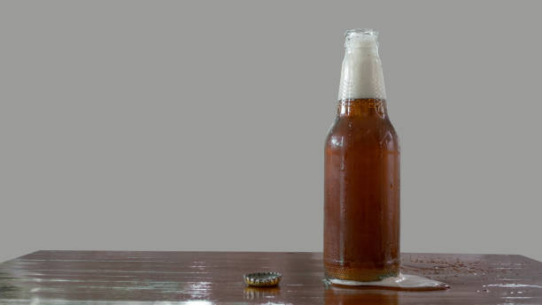 istock Beer bottle with openned bottlecap, foam split out on table 823410854