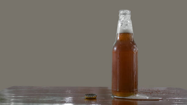 istock Beer bottle with openned bottlecap, foam split out on table 823410912