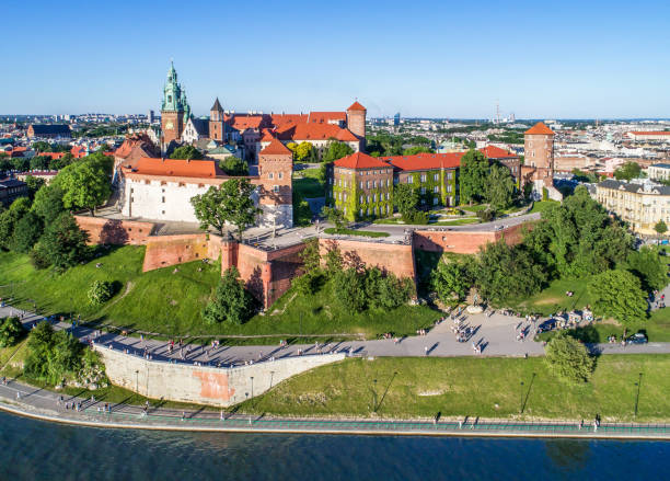 Wawel castle and Vistula River in Krakow, Poland Krakow, Poland – May 28, 2017: Wawel hill with historic royal castle and cathedral, Vistula River, park and walking people. Aerial view at sunset. wawel cathedral photos stock pictures, royalty-free photos & images