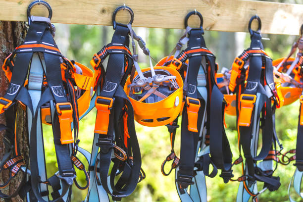 klettern ausrüstung ausrüstung - orange helm kabelbaum zip line sicherheitsausrüstung hängend auf einem brett. touristischen sommerzeit abenteuer park familien- und team-building-konzept für extreme freizeit sport - zip lining stock-fotos und bilder