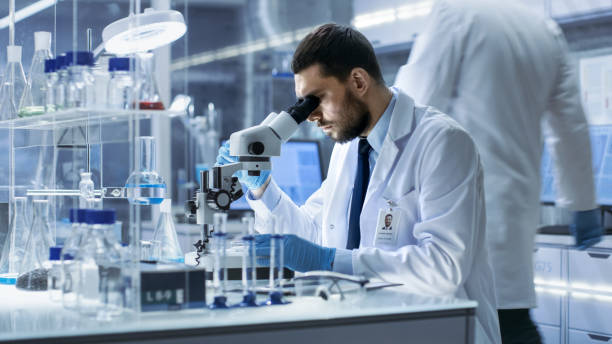 istock Research Scientist Looks into Microscope in Research Centre. He's Conducts Experiments in Modern Laboratory. 823447552