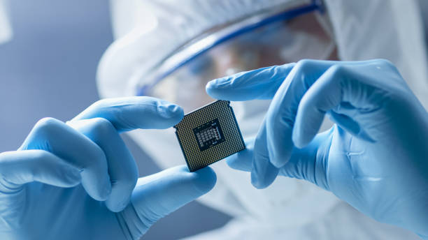 in ultra modern electronic manufacturing factory design engineer in sterile coverall holds microchip with gloves and examines it. - circuit board computer chip mother board electrical component imagens e fotografias de stock