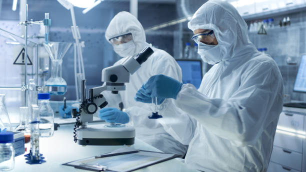 istock In a Secure High Level Laboratory Scientists in a Coverall Conducting a Research. Chemist Adjusts Samples and His Colleague Writes Down Results. 823447836