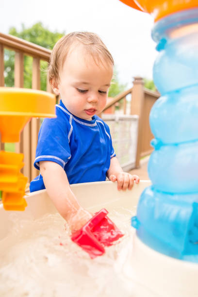 istock Toddler Boy Playing With Outdoor Water Table on Deck 823460118