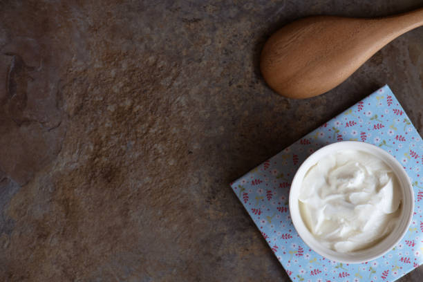 istock Sour cream in a bowl on brown marble background. 823465492
