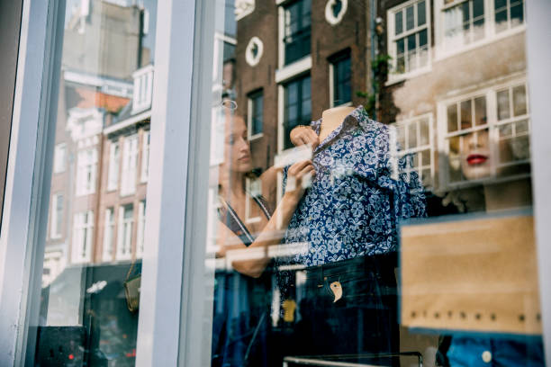 mujer joven que trabaja en un escaparate - shopping window fotografías e imágenes de stock