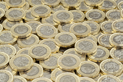 Wrexham, UK - April 10, 2017: Hoard of money. Lots of coins scattered in a large pile. New British pound coins introduced in 2017