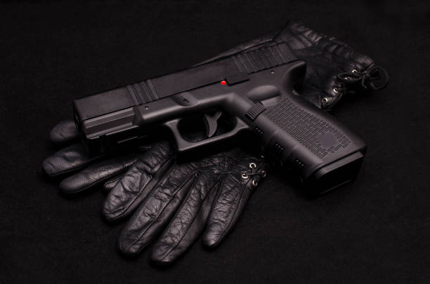 istock Black pistol and black leather gloves on black background 823492784