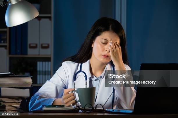 Unhappy Doctor With Headache Stressed Holding Coffee Stock Photo - Download Image Now