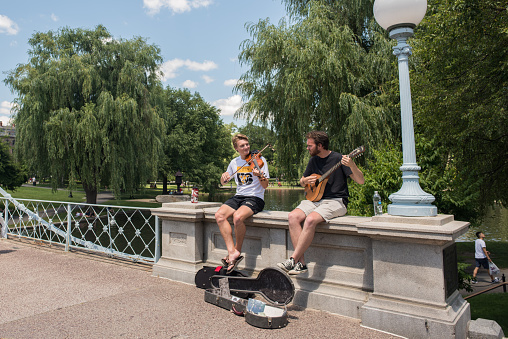 Boston, MA, July 4,2017: On Independence Day, two young friends play music for tips in the famous Boston Public Gardens.