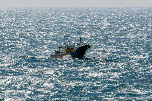 Small chinese trawler pounds through rough seas as it crosses the South China sea.