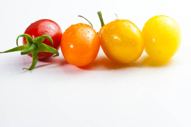 few cherry tomatoes in a row for color nuance on white background.