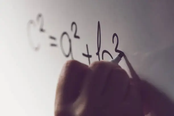Pythagorean theorem, also known as Pythagoras's theorem, math class in the school with teacher writing mathematical formula on white board, selective focus