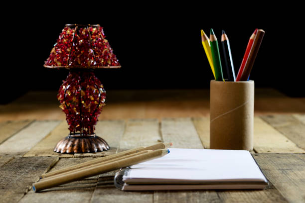Sketchbook on old table with old sensual lamp. Black background and old table