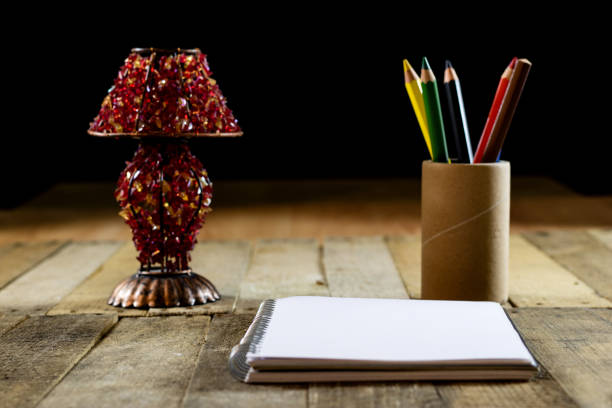 Sketchbook on old table with old sensual lamp. Black background and old table