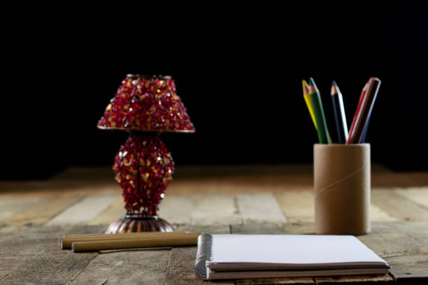 Sketchbook on old table with old sensual lamp. Black background and old table