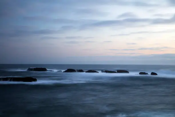 Photo of seascape view at sunset with rocks formation out in the Pacific ocean.
