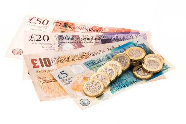British currency banknotes and one pound coins British currency banknotes and one pound coins - studio shot with a white background british currency stock pictures, royalty-free photos & images