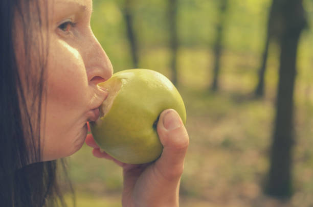 istock Cheerful girl grimaces and bites a green apple. 823581006