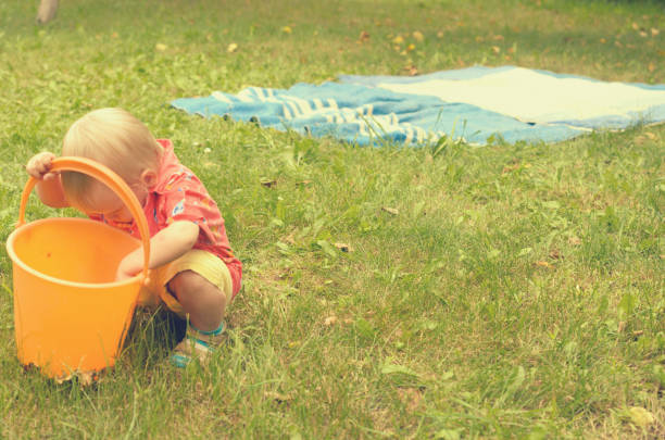 istock Little girl is playing with an empty bucket. 823582264