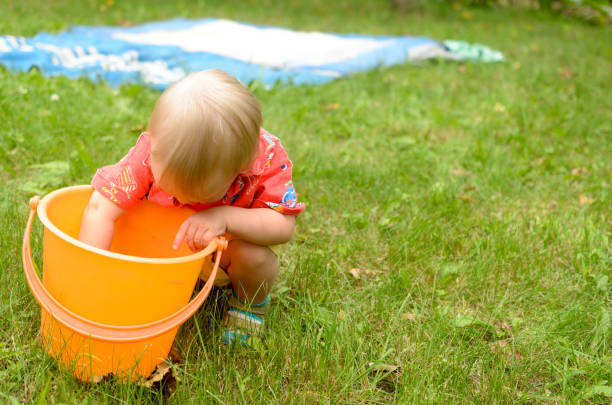 istock Little girl is playing with an empty bucket. 823585784