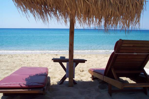 istock Idyllic sun umbrella and two empty deckchairs near sea 823605786