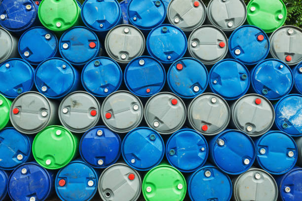 barils de pétrole bleu, gris et vert sur un pieu, usine de produits chimiques, des fûts de stockage en plastique, - oil distribution photos et images de collection