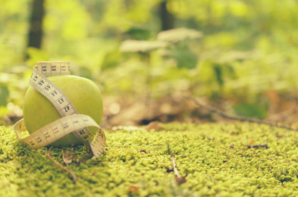 istock Green apple on green grass with measuring tape and without. 823615378
