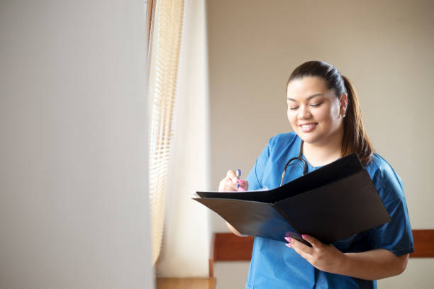 istock Young hispanic nurse smiling, holding a report and looking into folder she is holding in her hands 823616566