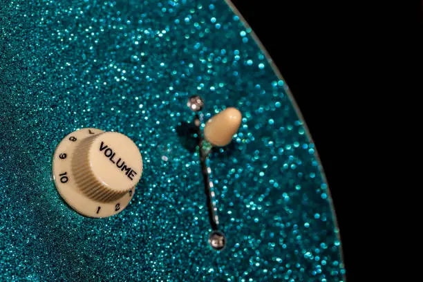 Turn up the volume. Control knob from a sparkly glam rock guitar. Loud music and fun party connotations.