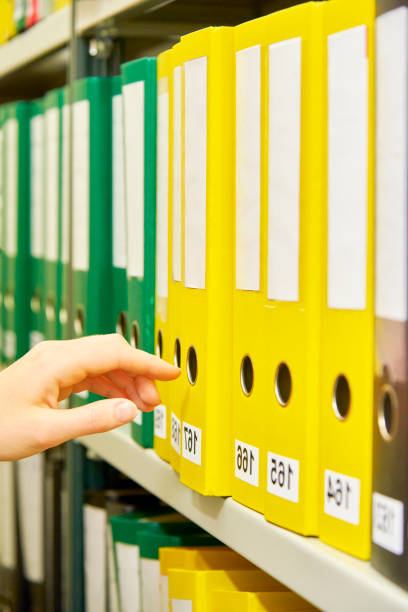 istock Yellow and green file folders in archive and human hand 823631632
