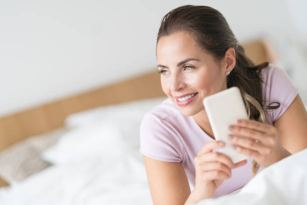 istock Beautiful woman in bed texting on her cell phone 823631668