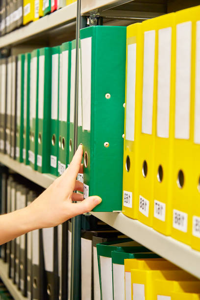 istock Yellow and green file folders in archive and human hand 823631674