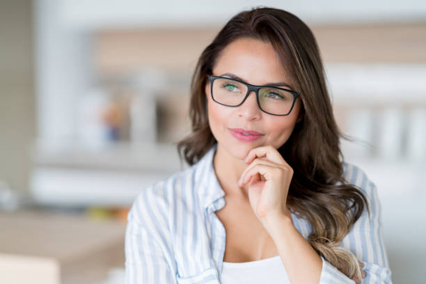 Thoughtful woman at home wearing eyeglasses